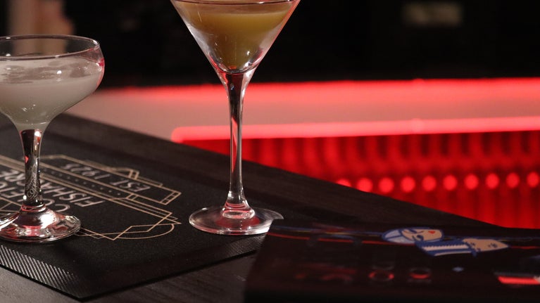 Cocktail glasses and the Savoy Cocktail book on a bar in a pop-up speakeasy at Coleton Fishacre in Devon